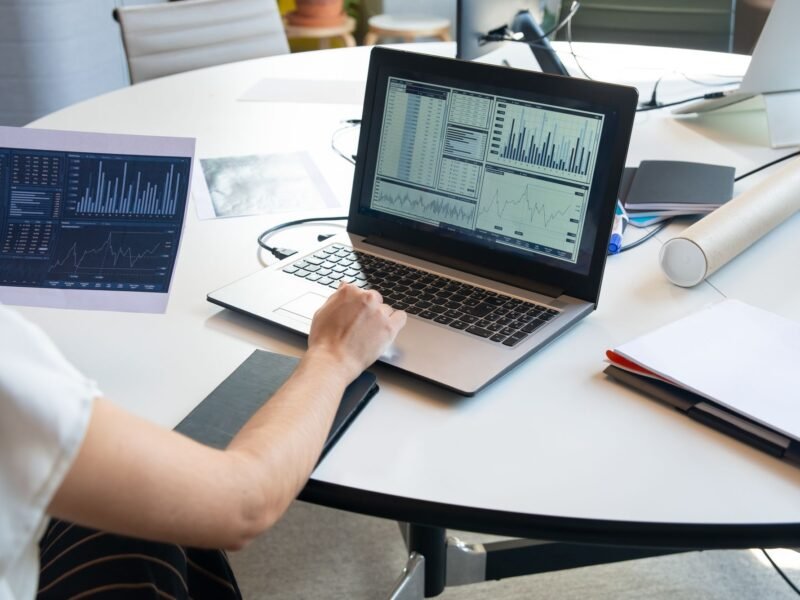 Printed performance graphs beside a laptop on a desk